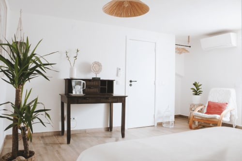 Quarto minimalista luminoso na Vila Vale Guest House com escrivaninha de madeira, plantas em vaso e luminária de teto em vime