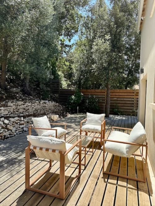 Terrasse en bois avec fauteuils blancs rembourrés aux Villas d'A Storia à Porto-Vecchio, entourée de pins