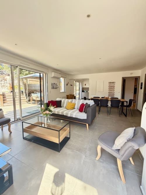 Salon moderne de la Villa Amandine à Porto-Vecchio avec séjour ouvert, salle à manger et portes vitrées donnant sur l'extérieur