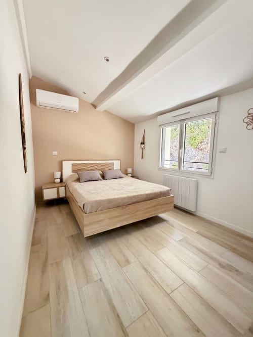 Chambre moderne avec lit en bois et mur d'accent beige aux Villas d'A Storia, Porto-Vecchio