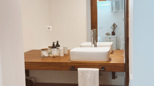 Banheiro moderno na Suíte Sunrise da Vila Vale Guest House com pias de cerâmica branca, bancada de madeira e amenidades