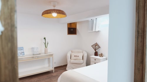 Quarto Sunrise Suite da Vila Vale Guest House com poltrona creme, luminária de vime e móveis modernos