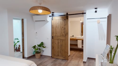 Suite Sunrise Moderno da Vila Vale Guest House com porta celeiro em madeira, luminária pendente tecida, plantas em vaso e banheiro privativo