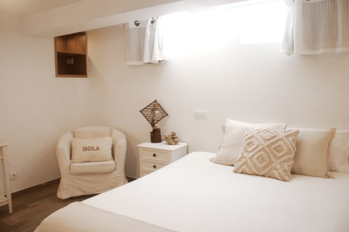 Suíte Sunrise da Vila Vale Guest House - quarto luminoso com roupas de cama creme, poltrona, criado e luz natural