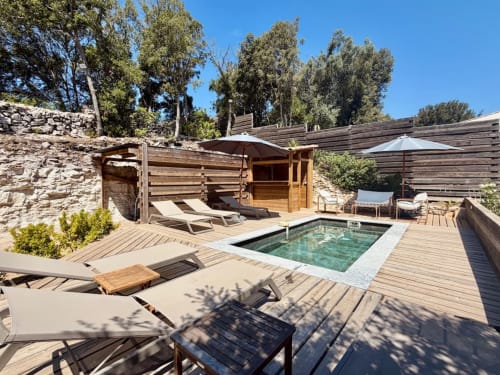 Terrasse piscine luxueuse aux Villas d'A Storia à Porto-Vecchio avec chaises longues, sauna en bois, parasols et eau turquoise cristalline