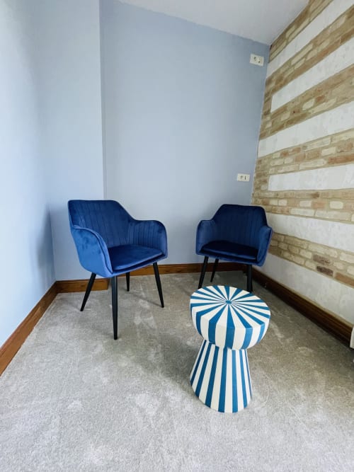 Coin salon moderne dans la Chambre 2 de la Maison Nolette avec fauteuils en velours bleu et table d'appoint rayée
