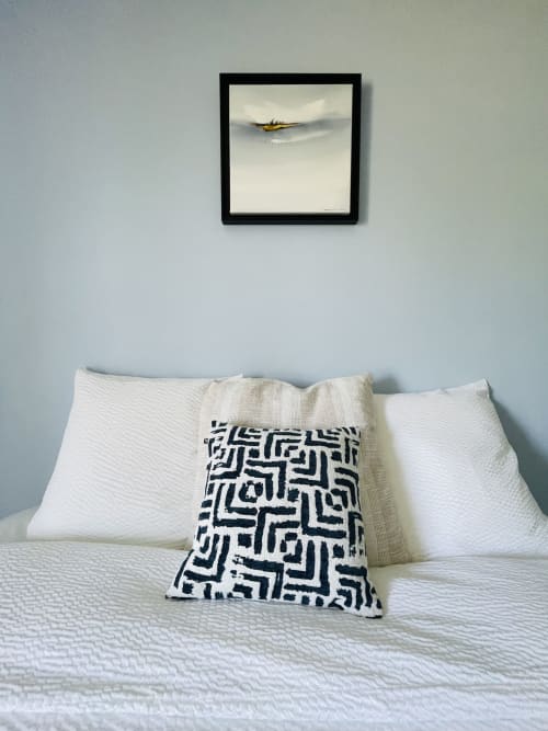 Chambre de la Maison Nolette avec oreillers blancs, coussin à motifs géométriques et tableau d'avion encadré au-dessus du lit