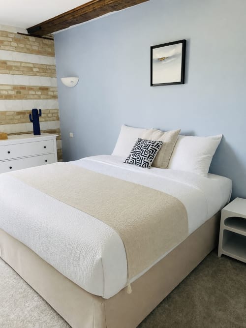 Chambre à la Maison Nolette avec lit queen-size, murs bleu clair, poutre bois apparente et mur de briques striées
