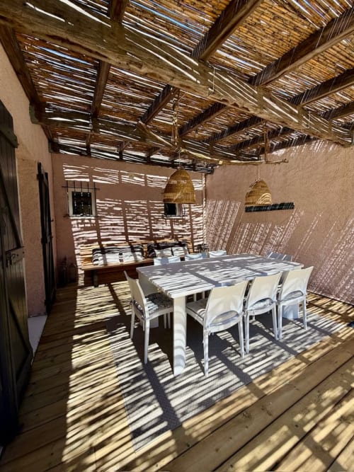 Terrasse couverte avec salle à manger à la villa Casa A Stonda à Porto-Vecchio, table en bois, chaises blanches et lumière naturelle