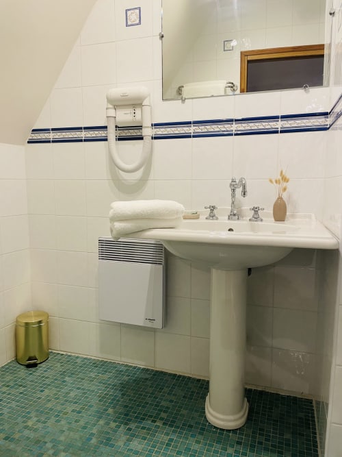 Salle de bain lumineuse à la Maison Nolette avec lavabo sur colonne, radiateur mural et carreaux de sol bleu-vert à Noyelles sur Mer