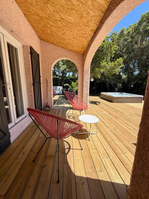 Terrasse avec chaises rouges et table blanche à la villa Les Villas d'A Storia à Porto-Vecchio, vue sur la piscine