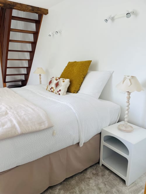 Chambre lumineuse à la Maison Nolette avec lit blanc, coussin moutarde, échelle en bois et lampe de chevet à Noyelles sur Mer