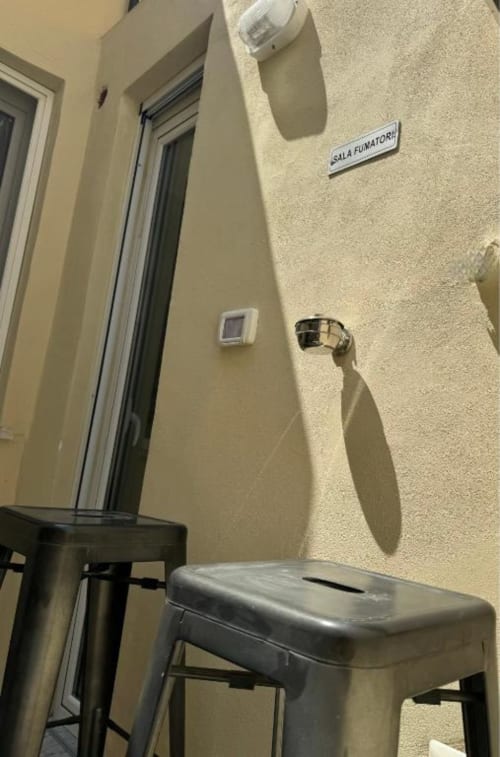 Ingresso zona fumatori presso Maison ì Room a Reggio di Calabria con sgabello metallico e pannello di controllo