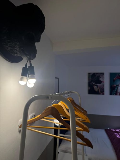 Camera da letto con appendiabiti in legno su asta e lampada a sospensione a forma di uccello presso Maison ì Room a Reggio Calabria