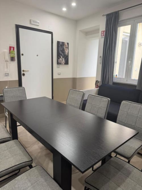 Moderna zona pranzo in appartamento trilocale presso Maison ì Room con tavolo nero, sedie grigie e arredamento contemporaneo a Reggio
