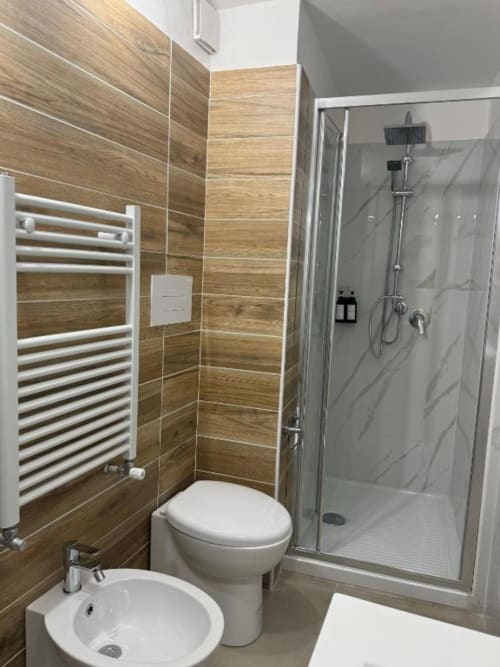 Bagno moderno nell'appartamento Maison ì Room a Reggio di Calabria, con pareti in legno-piastrelle, wc bianco, lavandino e porta-asciugamani