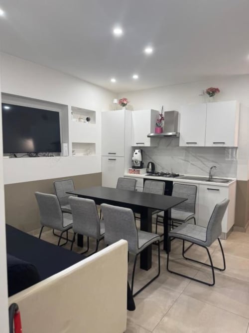 Moderna cucina open-plan e zona pranzo a Maison ì Room a Reggio di Calabria con cabinetry bianca e tavolo da pranzo nero