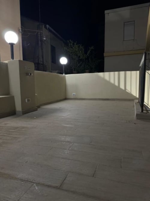 Ampia terrazza dell'Appartamento bilocale Maison ì Room a Reggio di Calabria, illuminata da eleganti luci notturne