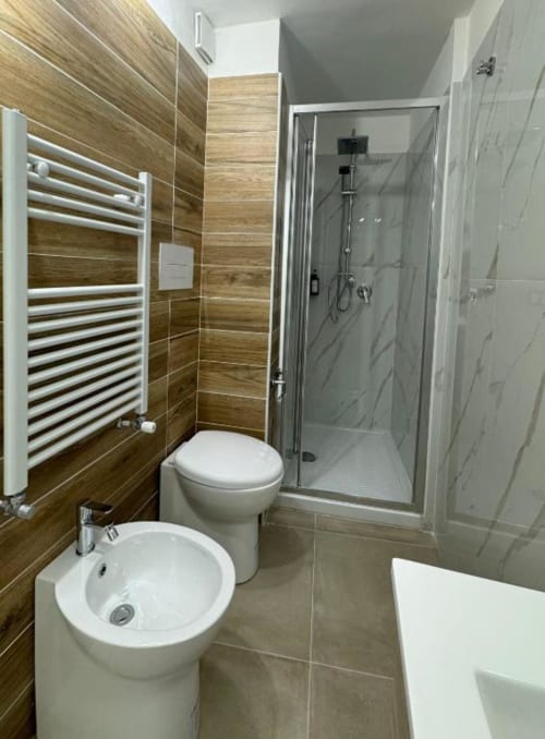 Moderno bagno nell'appartamento di Reggio di Calabria con pareti in piastrelle in legno, bidet e wc bianchi, scaldasalviette riscaldato, e