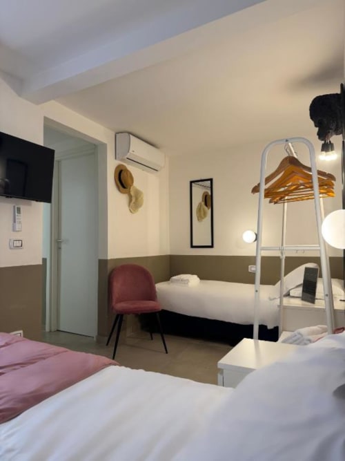 Camera moderna con letti gemelli, scaffale in legno con scala, sedia rossa e aria condizionata a Maison ì Room