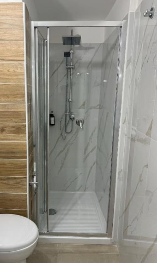 Moderno box doccia con pareti in marmo e soffione a pioggia nell'Appartamento Bilocale presso Maison ì Room a Reggio di