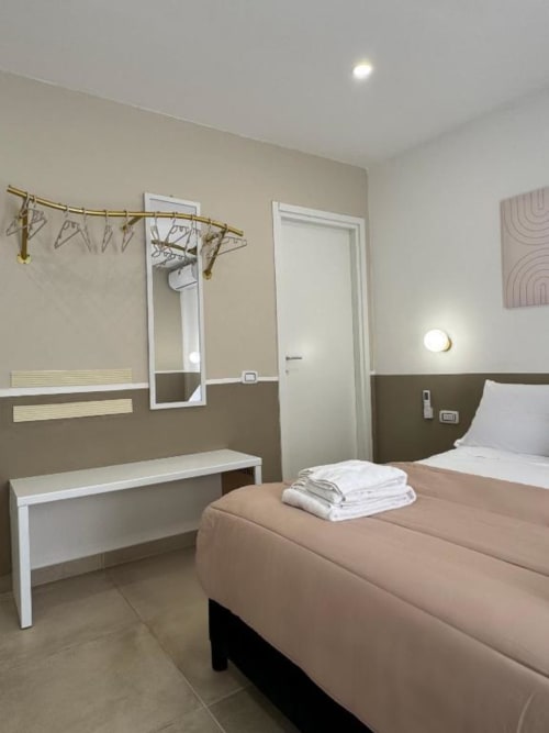 Camera da letto moderna nell'appartamento di Reggio di Calabria con letto, specchio, panchetta in legno e arredi contemporanei