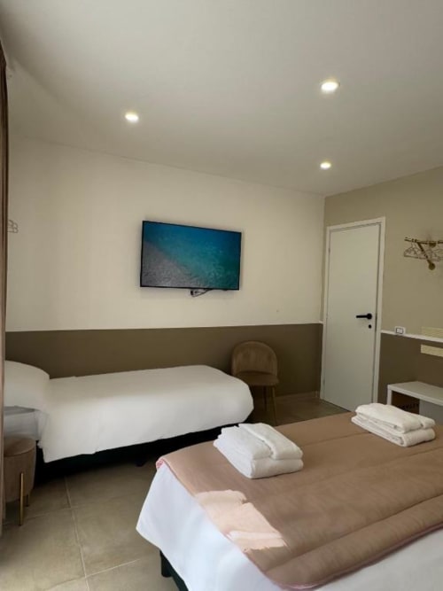 Camera moderna della Maison ì a Reggio di Calabria con due letti, TV a parete e arredamento contemporaneo bicolore