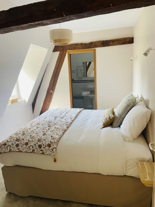 Chambre douillette à la Maison Nolette avec poutres apparentes, literie crème et accès à salle d'eau privée