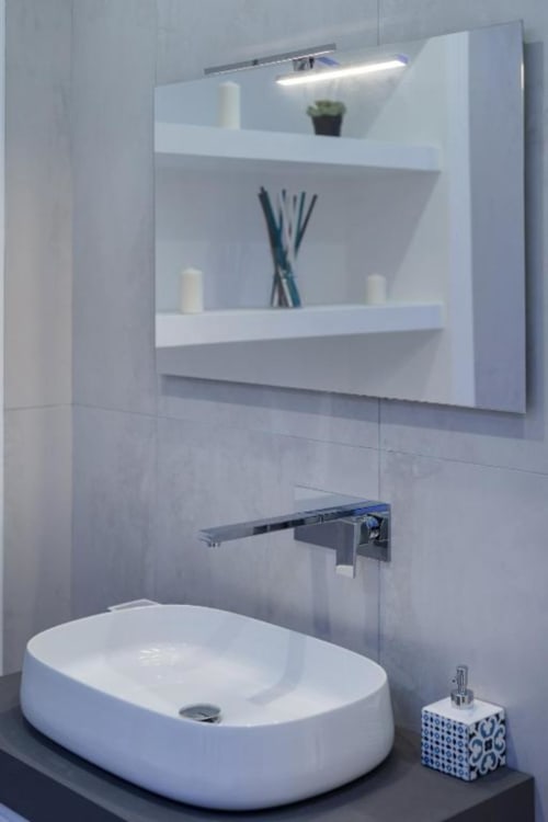 Bagno moderno a IL POETA Procida con lavabo ovale bianco, rubinetto a parete, specchio illuminato e mensole organizzate