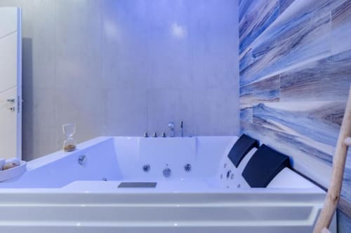 Vasca idromassaggio lussuosa con getti d'acqua e rivestimento in marmo blu nella suite IL POETA, Procida.