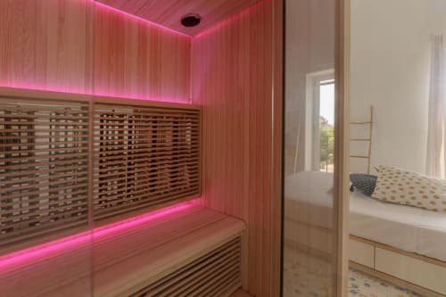 Sauna moderna con illuminazione neon rosa e interni in legno nella suite IL POETA, Procida