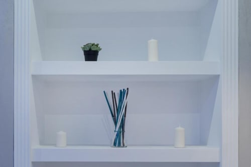 Elegante scaffalatura bianca minimalista nella suite IL POETA con candele, pianta grassa e diffusore di aromi blu come elementi decorativi