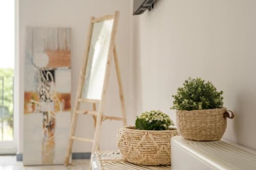 Luminosa camera minimalista a IL POETA Procida con piante in vasi decorati sul davanzale, specchio in legno e vista costiera