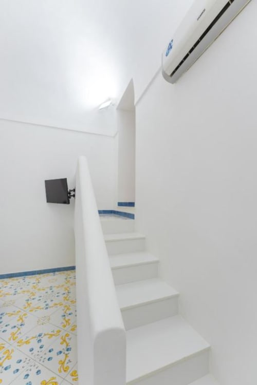 Scala moderna nell'appartamento Il Poeta a Procida con gradini bianchi, accenti in piastrelle blu e pavimento decorato