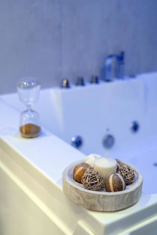 Arredamento spa nel bagno di IL POETA Procida con diffusori aromatici, clessidra e candela su vanità bianca