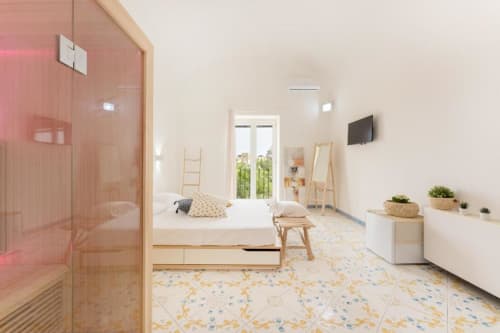 Suite moderna con sauna a IL POETA a Procida: letto, cabina doccia in vetro, dettagli in legno e arredamento minimalista