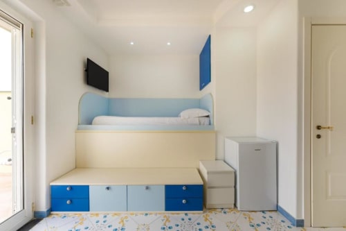 Camera da letto moderna in appartamento IL POETA Procida con letto a soppalco integrato, accenti blu e mobili con ripostiglio integrato