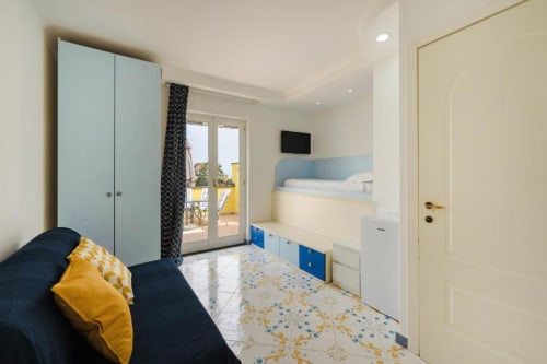 Camera moderna di IL POETA a Procida con letto blu navy, zona notte soppalcata, armadio azzurro e accesso alla terrazza