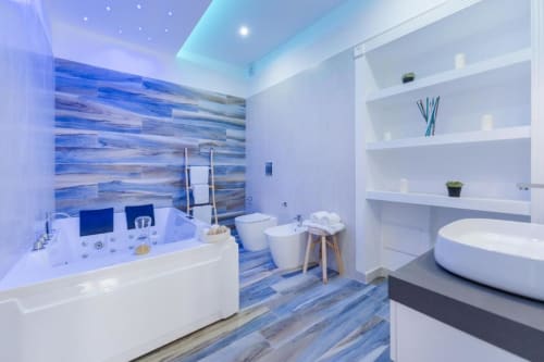 Lussuoso bagno moderno di IL POETA Procida con piastrelle blu, vasca idromassaggio, bidet, wc e arredo sospeso bianco