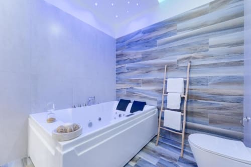 Moderna suite da bagno a IL POETA Procida con vasca idromassaggio, parete in legno, scaletta portasciugamani e toilette