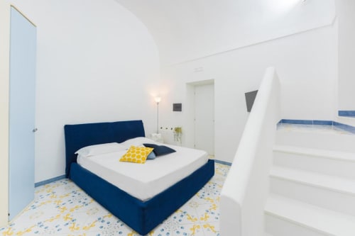 Camera da letto moderna a Il Poeta B&B a Procida con letto blu navy, pareti bianche e piastrelle nautiche gialle