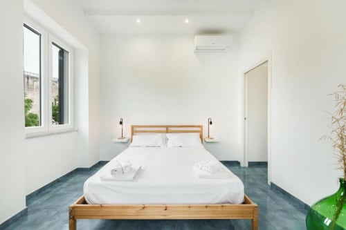 Camera moderna a IL POETA a Procida con letto in legno, biancheria bianca, aria condizionata, ampia finestra con vista panoramica e arredamento scuro
