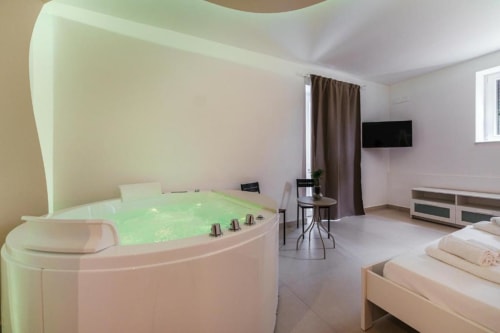 Camera King con Vasca Idromassaggio presso IL POETA, Procida - moderna camera da letto con vasca jacuzzi illuminata, TV a schermo piatto e vista giardino
