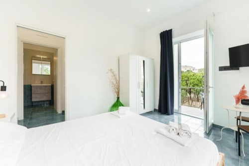 Luminosa camera quadrupla con balcone presso IL POETA a Procida, con letto bianco, bagno moderno e terrazza con vista sul paesaggio