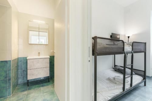 Camera quadrupla moderna a IL POETA a Procida con letti a castello in metallo e bagno ensuite con pareti piastrellate verdi