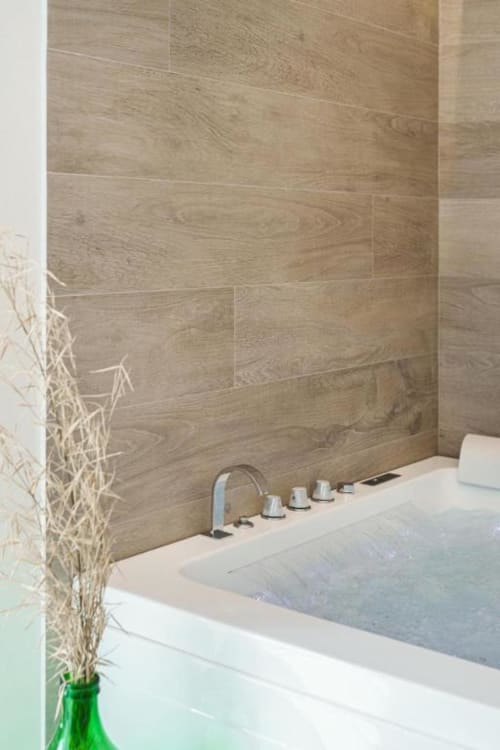 Vasca da bagno spa moderna con rivestimenti in piastrelle effetto legno e finiture cromate presso IL POETA luxury B&B a Procida
