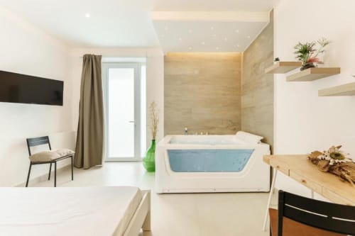 Bagno di lusso moderno in IL POETA Procida con vasca idromassaggio, pareti in marmo, mensole in legno e arredi eleganti