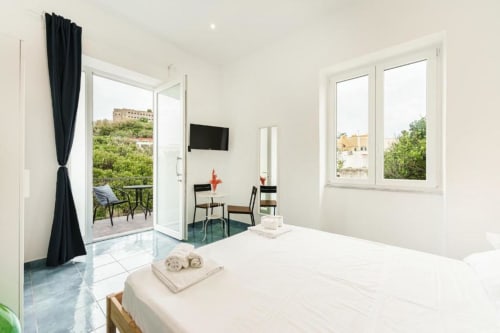 Luminosa camera quadrupla con balcone vista Procida, letto bianco, TV e terrazza - IL POETA B&B