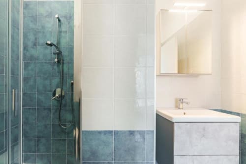 Bagno moderno presso IL POETA con doccia in piastrelle turchesi, lavabo bianco, specchio e box doccia in vetro a Procida