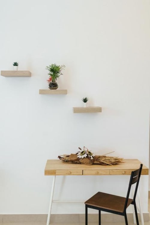 Spazio di lavoro minimalista in IL POETA Procida con scrivania in legno, piante in vaso su ripiani sospesi e décor naturale